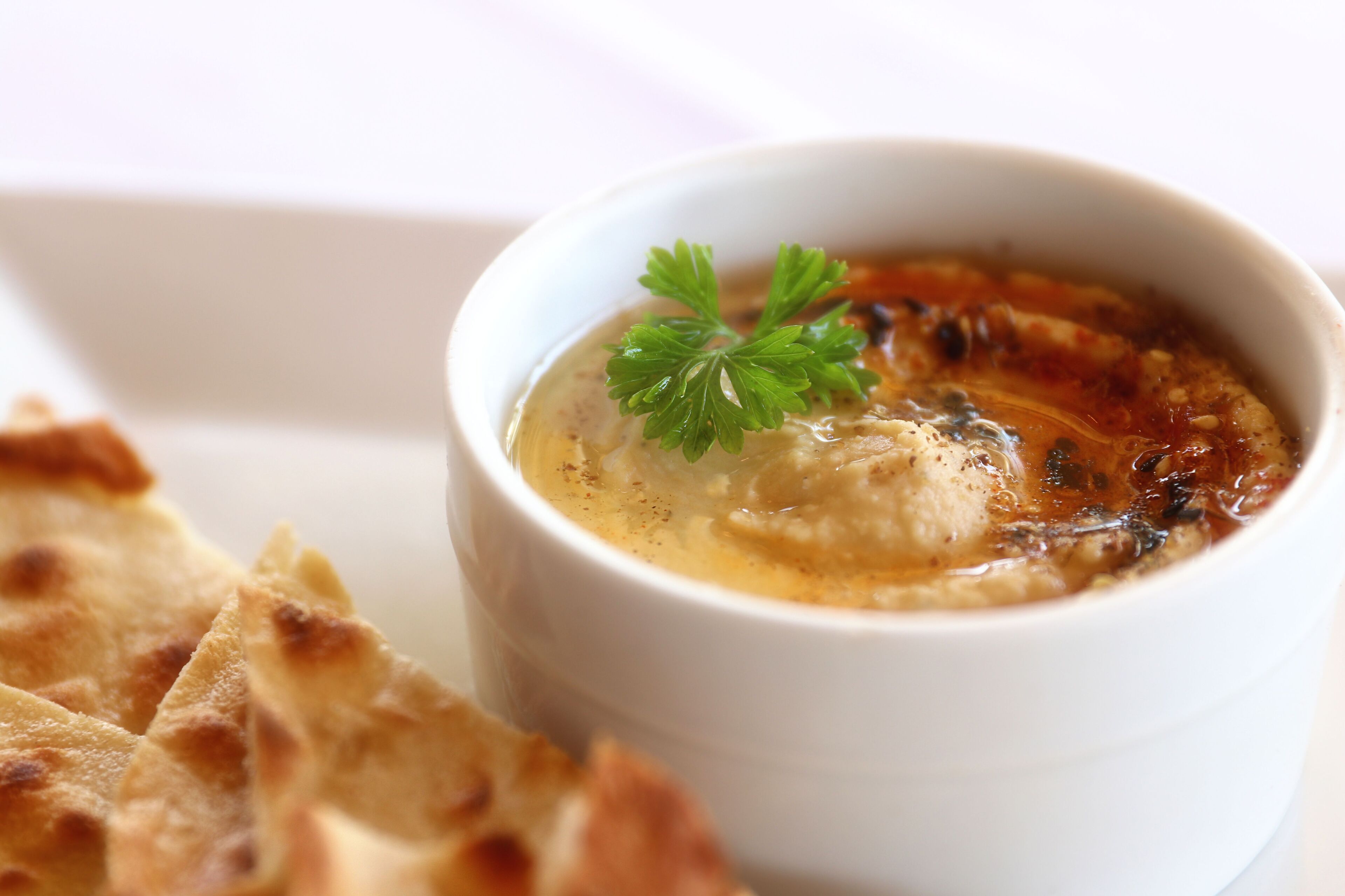 A bowl of soup with a garnish, accompanied by pieces of flatbread.