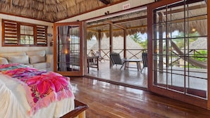 A room with a bed, a sofa, and a large window with a view of a patio area. - Portofino Beach Resort (San Pedro)