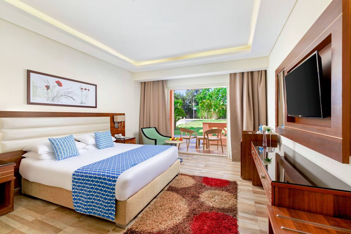 Een hotelkamer met een groot bed, een televisie, een bureau en uitzicht op de omgeving.