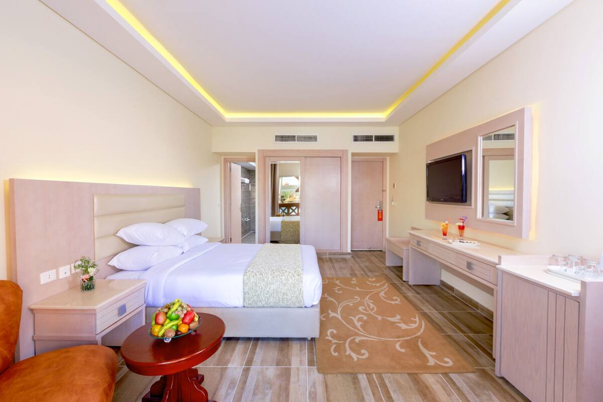 Hotelkamer met een bed, nachtkastjes, een televisie, een badkamer en een klein tafeltje met fruit.