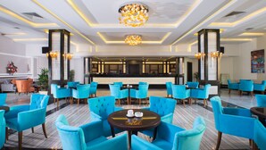 Un hall d’entrée spacieux, doté de chaises bleues modernes, d’une table ronde centrale et d’un lustre décoratif.