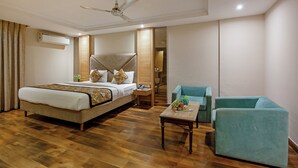 Une chambre d’hôtel avec un grand lit, un bureau, une chaise et un ventilateur de plafond.