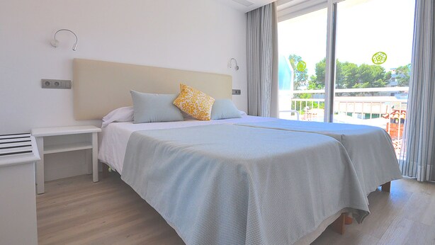 Een hotelkamer met een bed, nachtkastje en uitzicht op de omgeving.