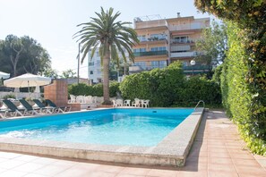 Una piscina techada, una piscina al aire libre, sombrillas