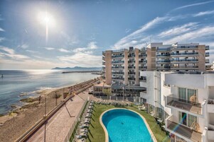 Una piscina al aire libre, sombrillas, sillones reclinables de piscina