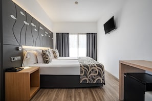 A modern hotel room with a bed, bedside table, TV, and a small refrigerator. - THB Gran Bahia Hotel and Apartments (Santa Margalida)