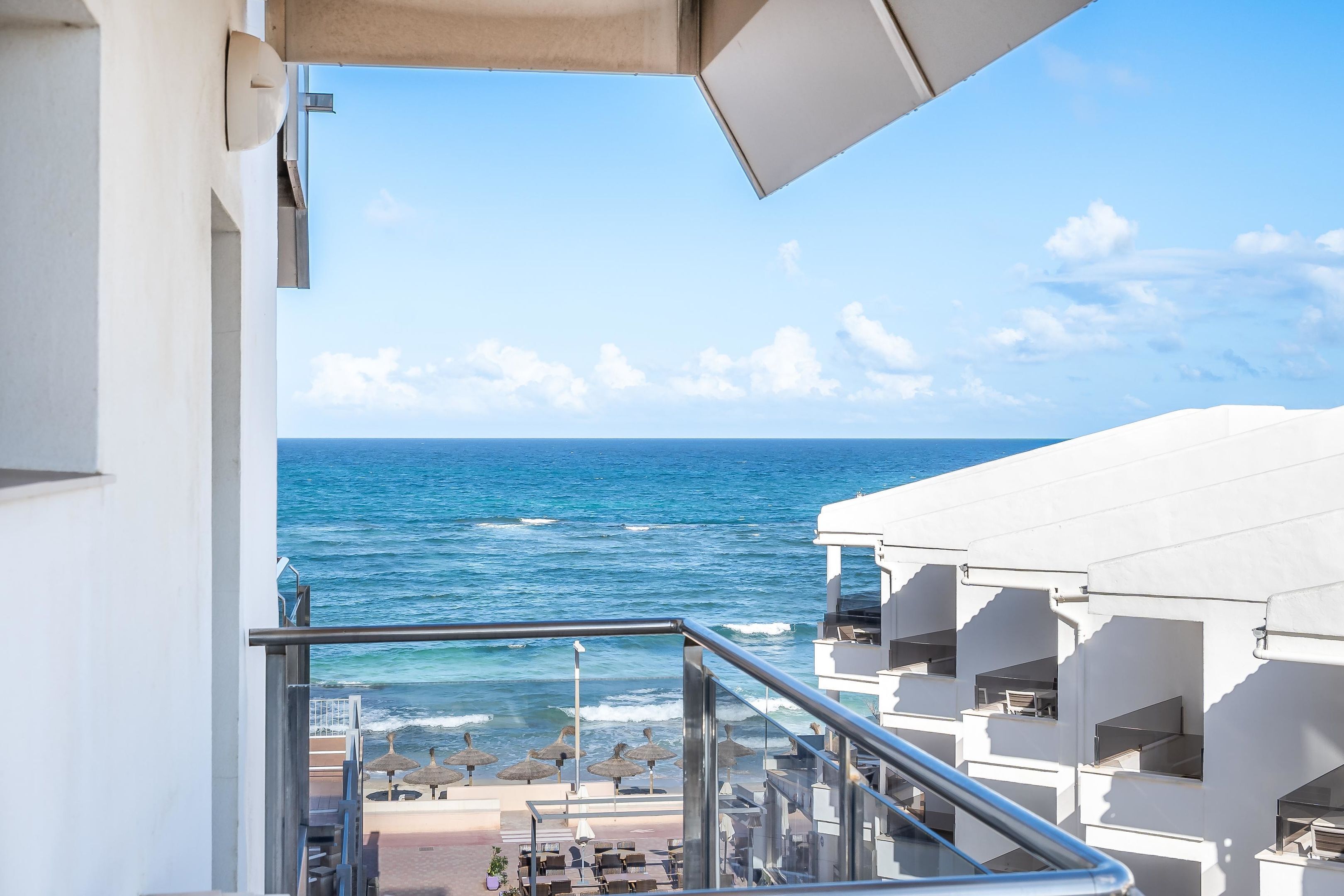 A balcony with a view of the ocean and beach umbrellas.