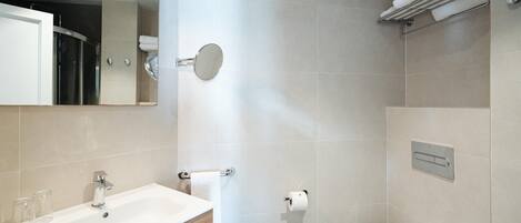 A modern bathroom with a sink, mirror, toilet, and towel rack.