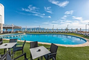 Una piscina al aire libre, sombrillas, sillones reclinables de piscina