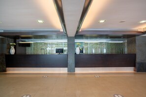 A modern reception area with a dark reception desk, a large pillar, and a glass partition. - THB Gran Bahia Hotel and Apartments (Santa Margalida)