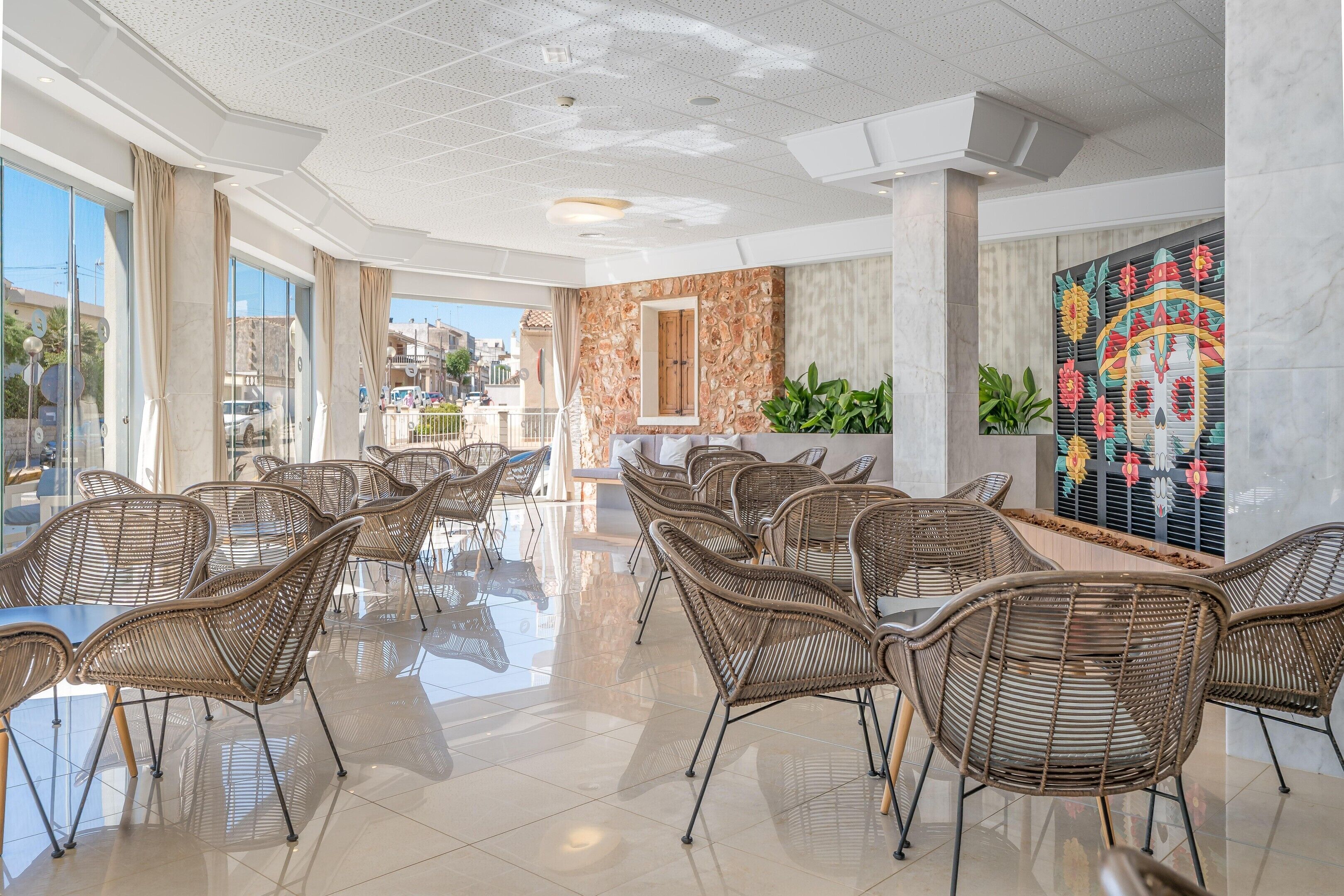 A hotel lobby with wicker chairs, a stone wall, and a colorful mural.