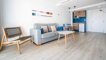 A modern living room with a grey sofa, wooden chair, and a small table.