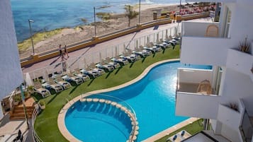 Una piscina al aire libre, sombrillas, tumbonas