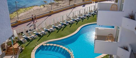 A swimming pool with a circular section and a beach view.