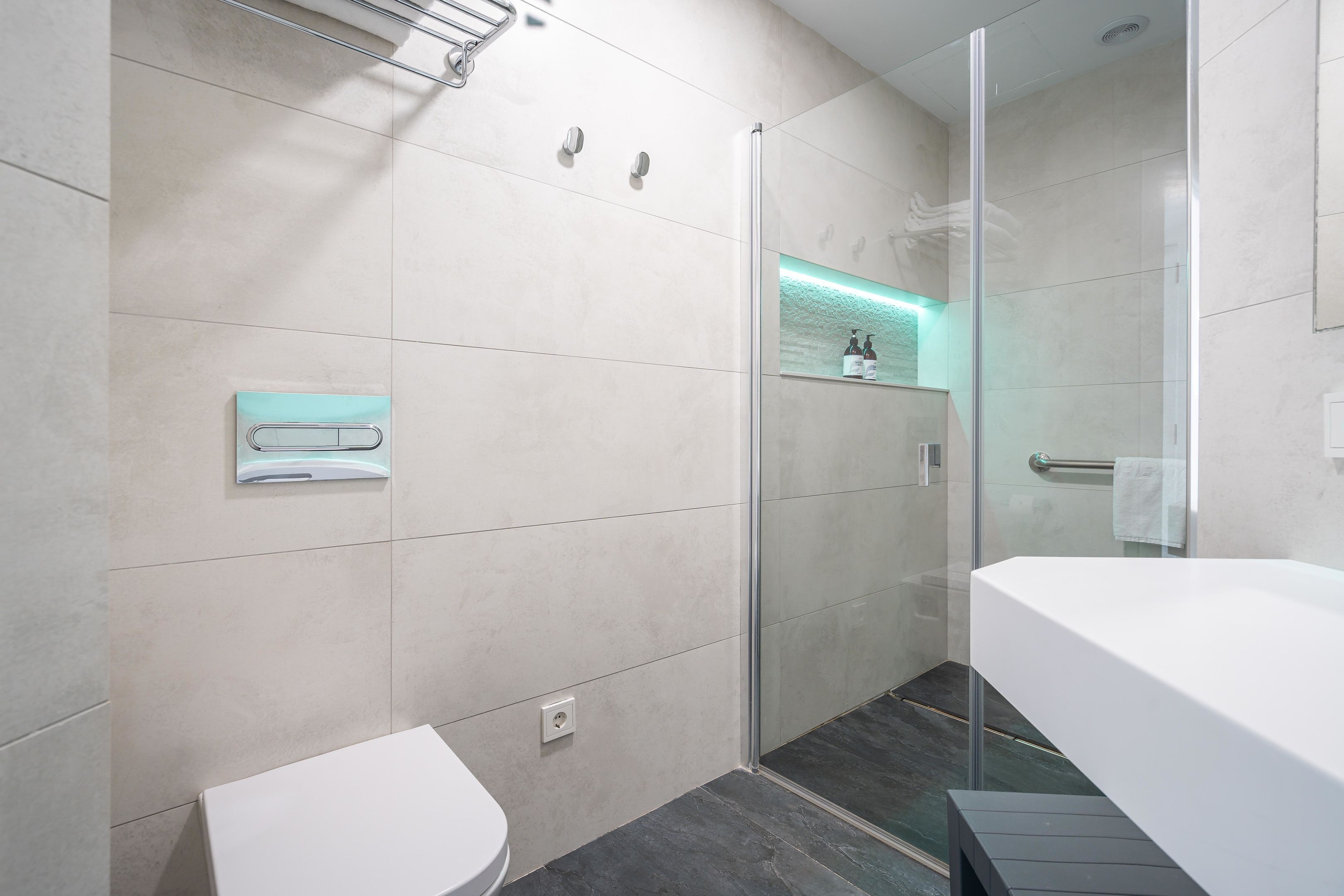 Un baño moderno con cabina de ducha de vidrio, un lavabo blanco y un inodoro.