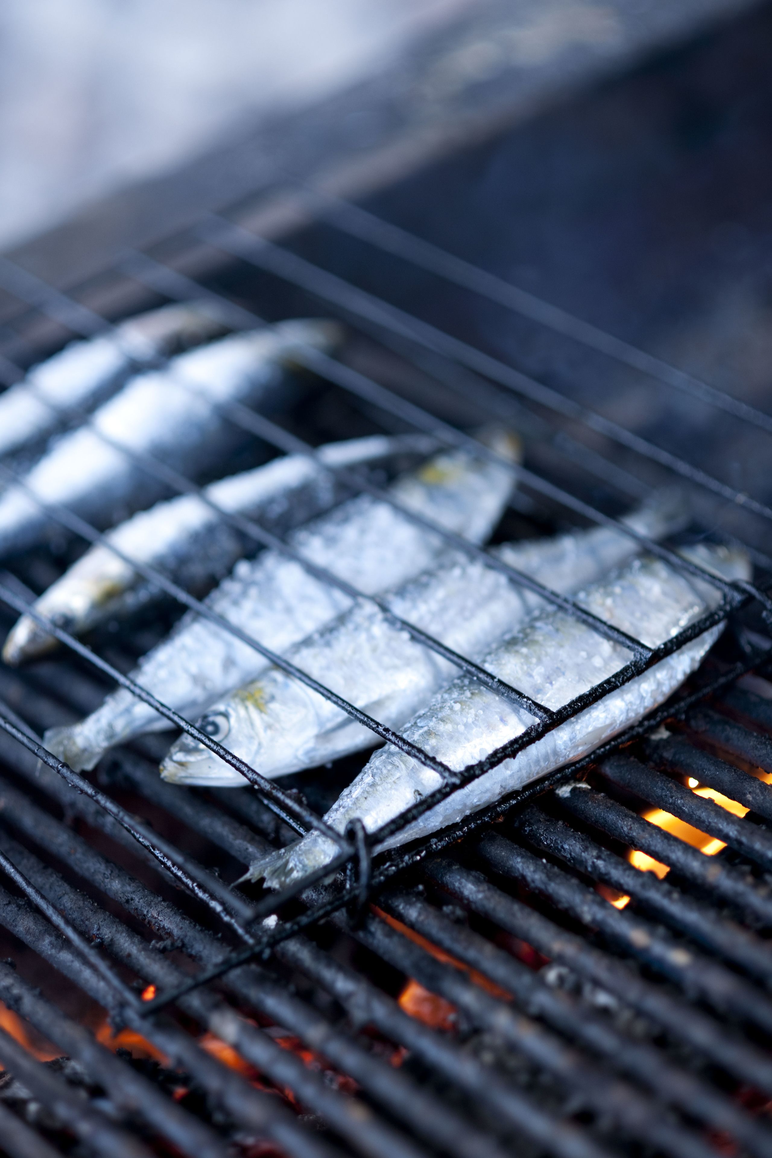 Gegrillter Fisch auf einem Grill mit deutlichen Grillstreifen und darunter Flammen.