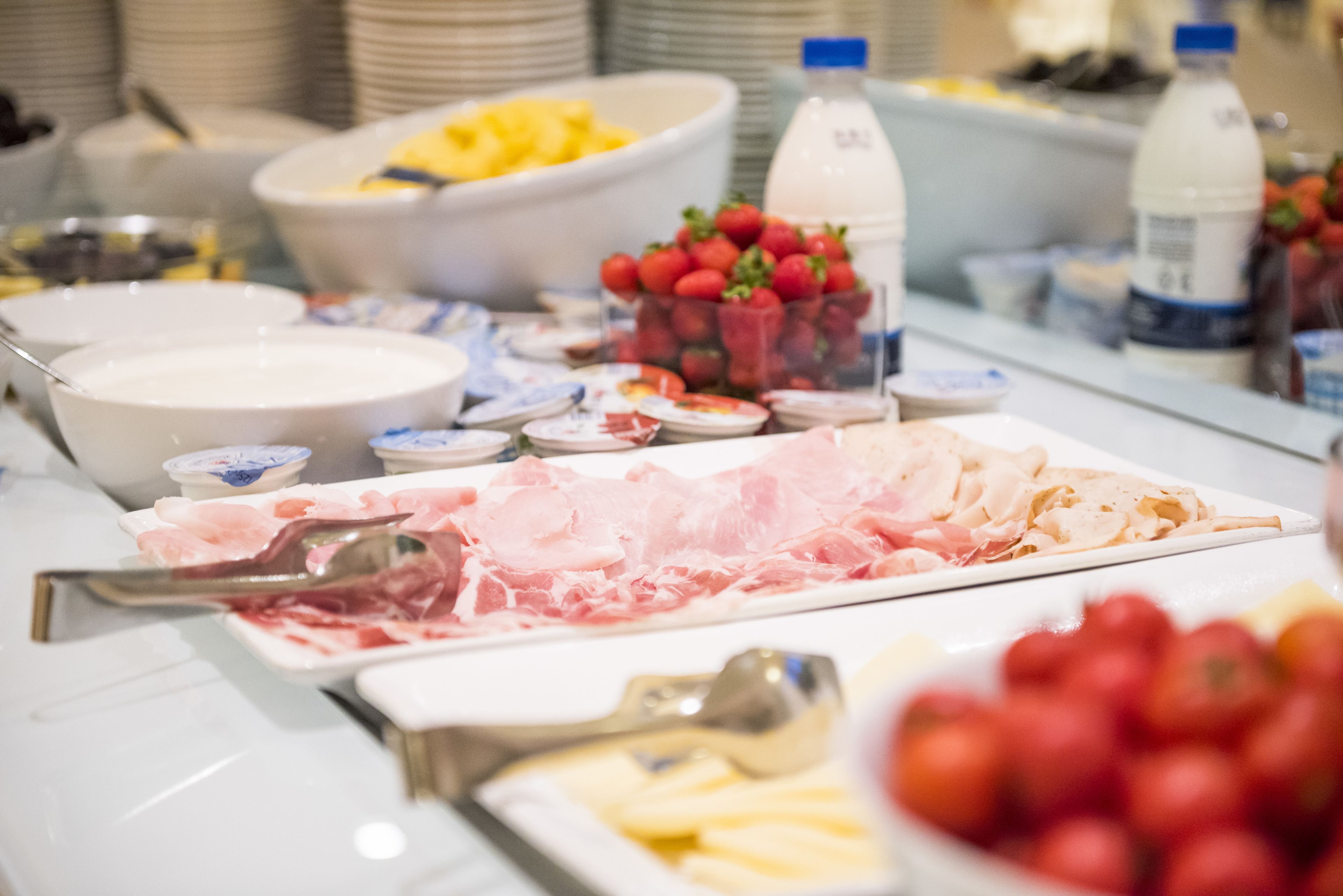 A buffet table with various food items including fruits, cheeses, and meats.