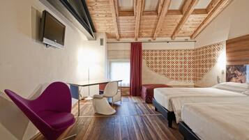 Habitación de hotel con techo de madera, televisor montado en la pared, escritorio con sillas, cama y pared con diseño.