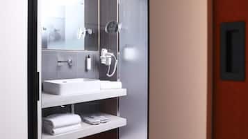 A modern bathroom with a white sink, a mirror, and a glass shower enclosure.