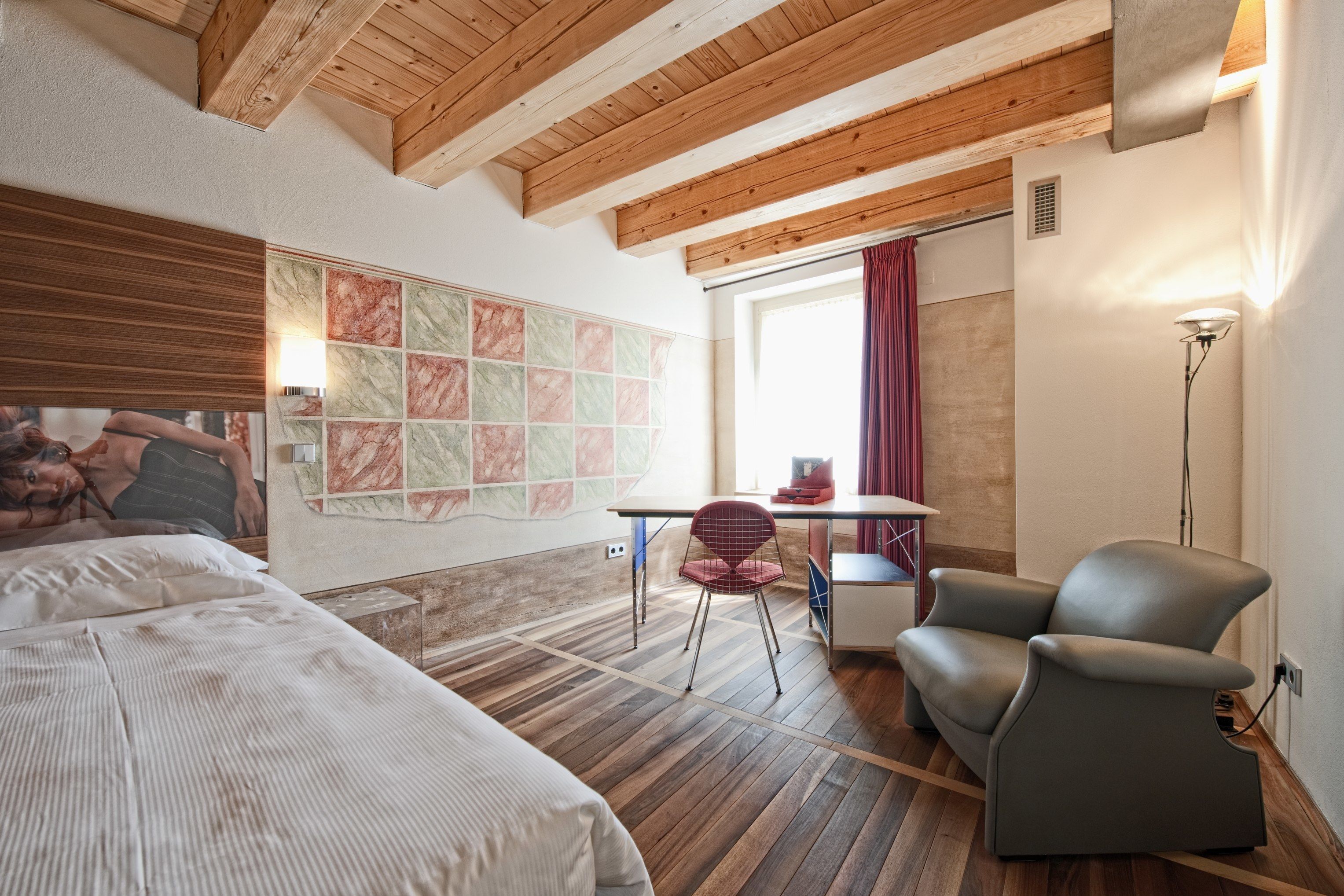Une chambre à coucher comprenant un lit, un bureau, une chaise et un mur orné d’un motif décoratif.