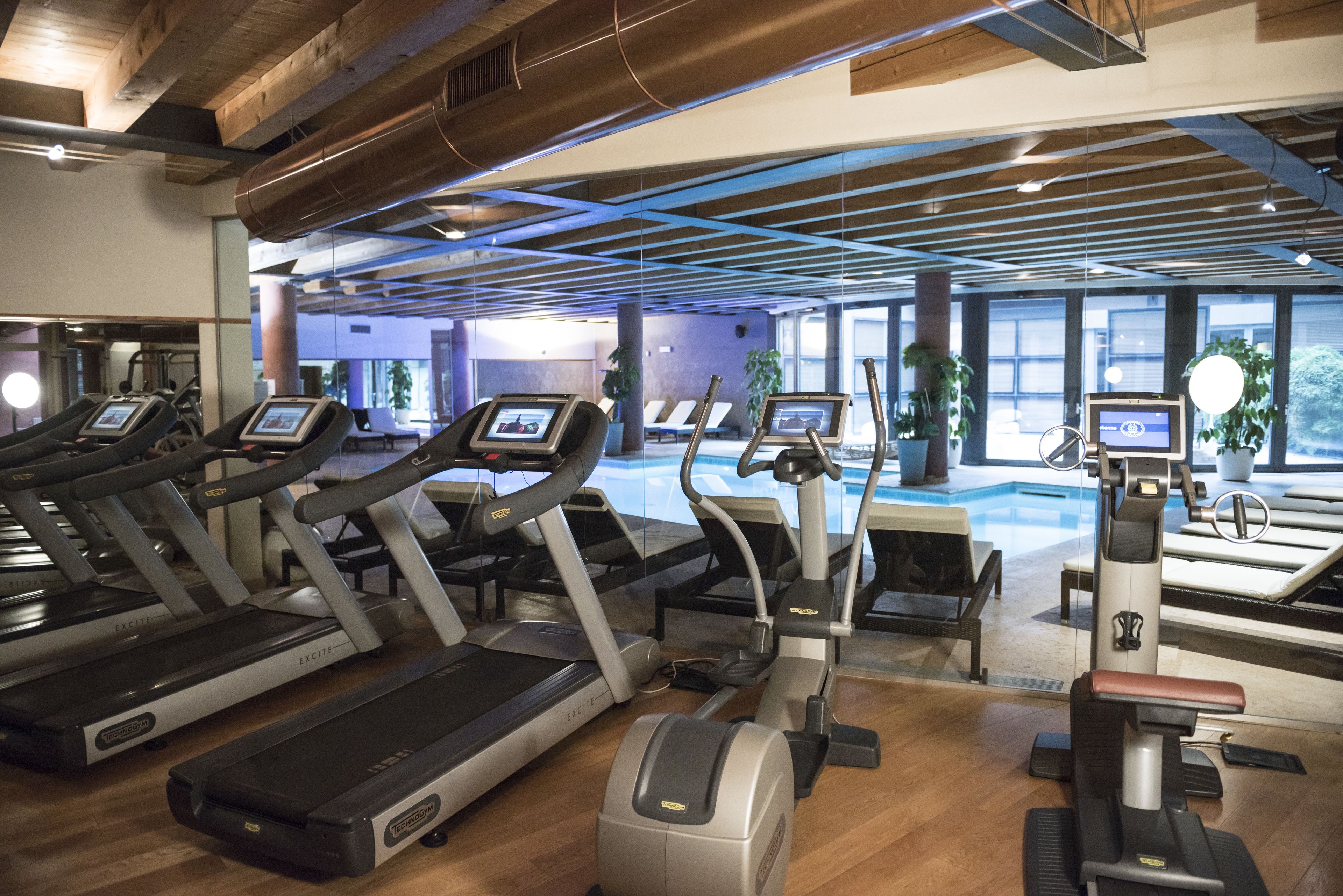 Ett gym med löpband, crosstrainers och ett poolområde.