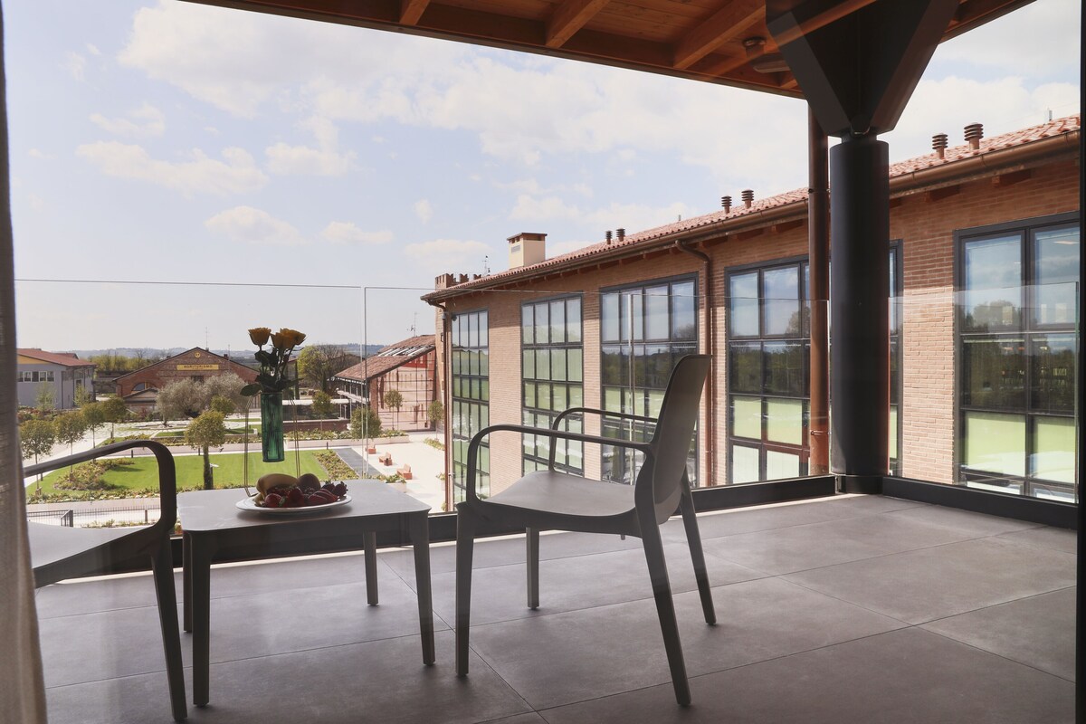 A balcony with a table, chairs, and a view of a brick building and surrounding area.