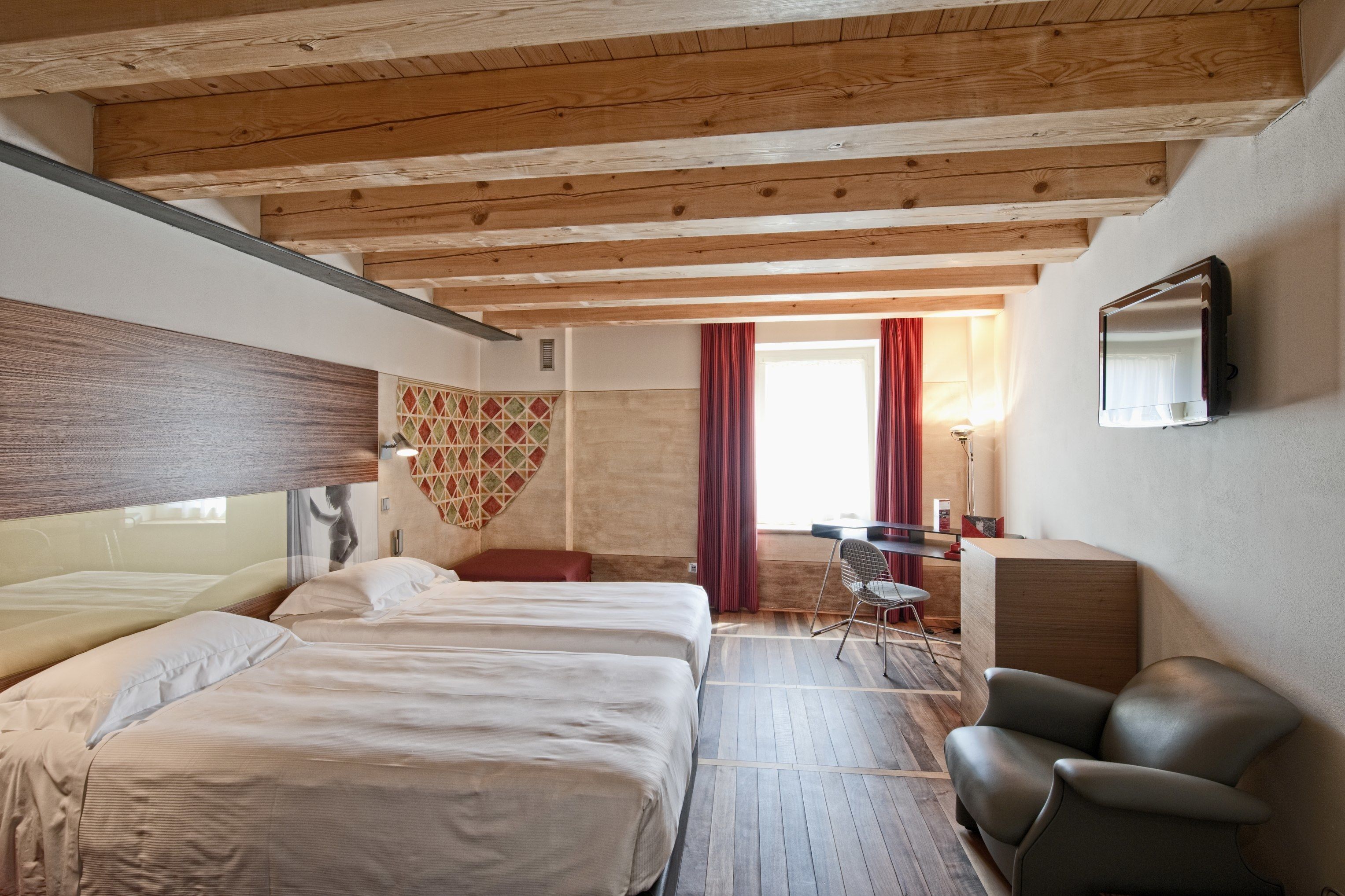 Ein Hotelzimmer mit zwei Betten, einem Schreibtisch, einem Stuhl und einem Fernseher.