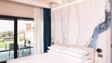 Ein modernes Hotelzimmer mit einem großen Bett, Blick auf die Stadt und einem Balkon mit Tisch und Stühlen.