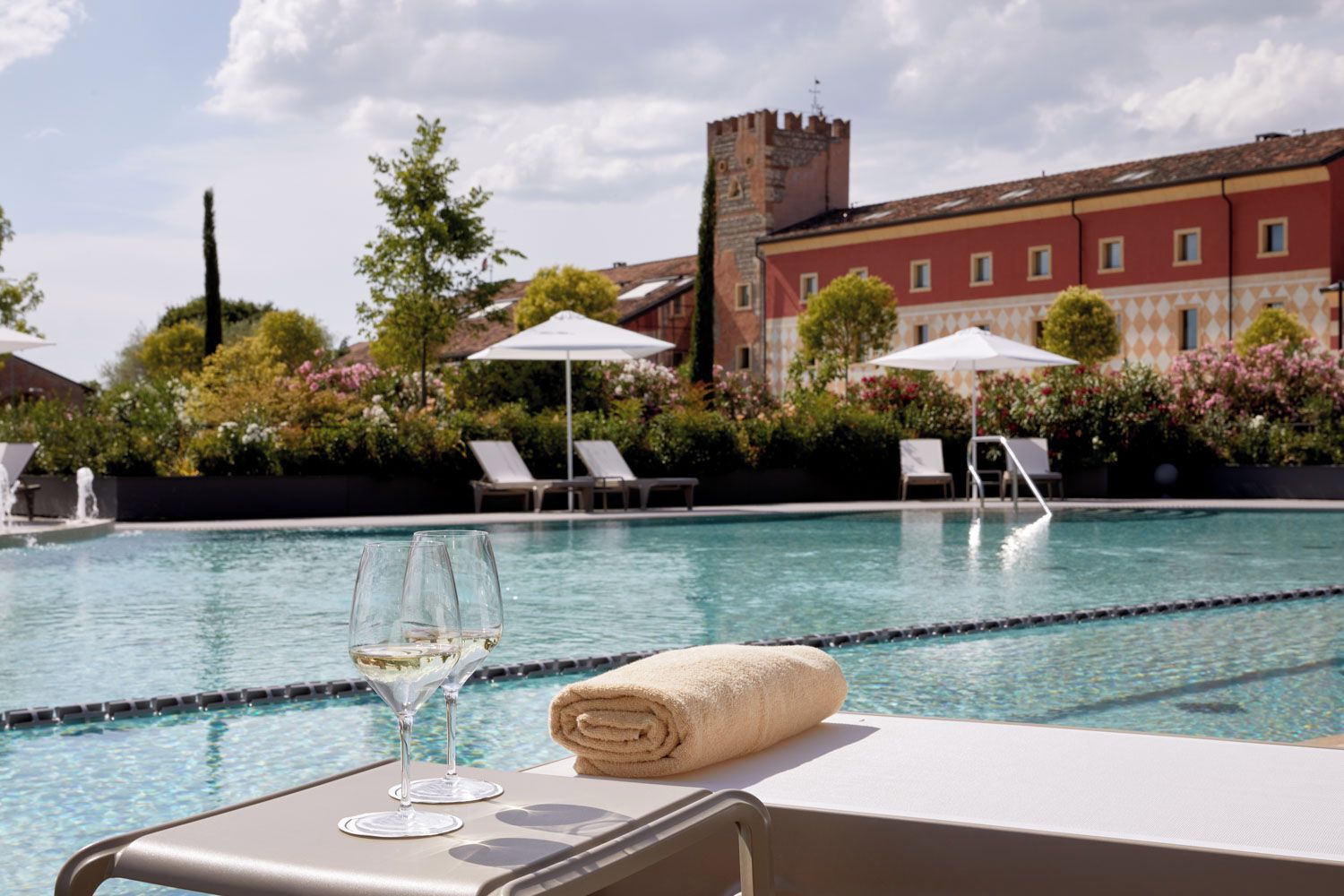 A poolside view with lounge chairs, a tower in the background, and a clear sky.