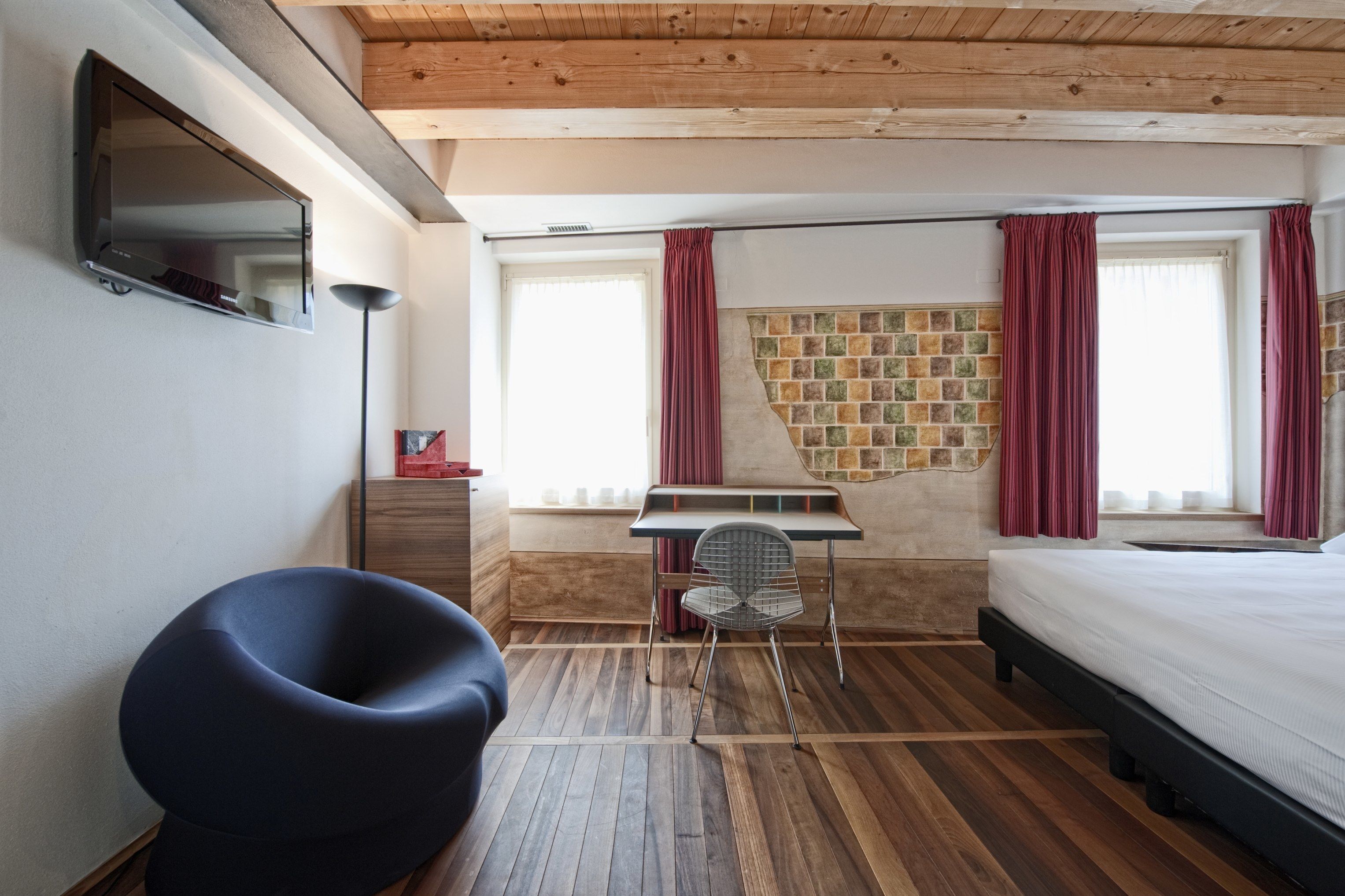 A bedroom with a bed, a desk, a chair, and a TV.
