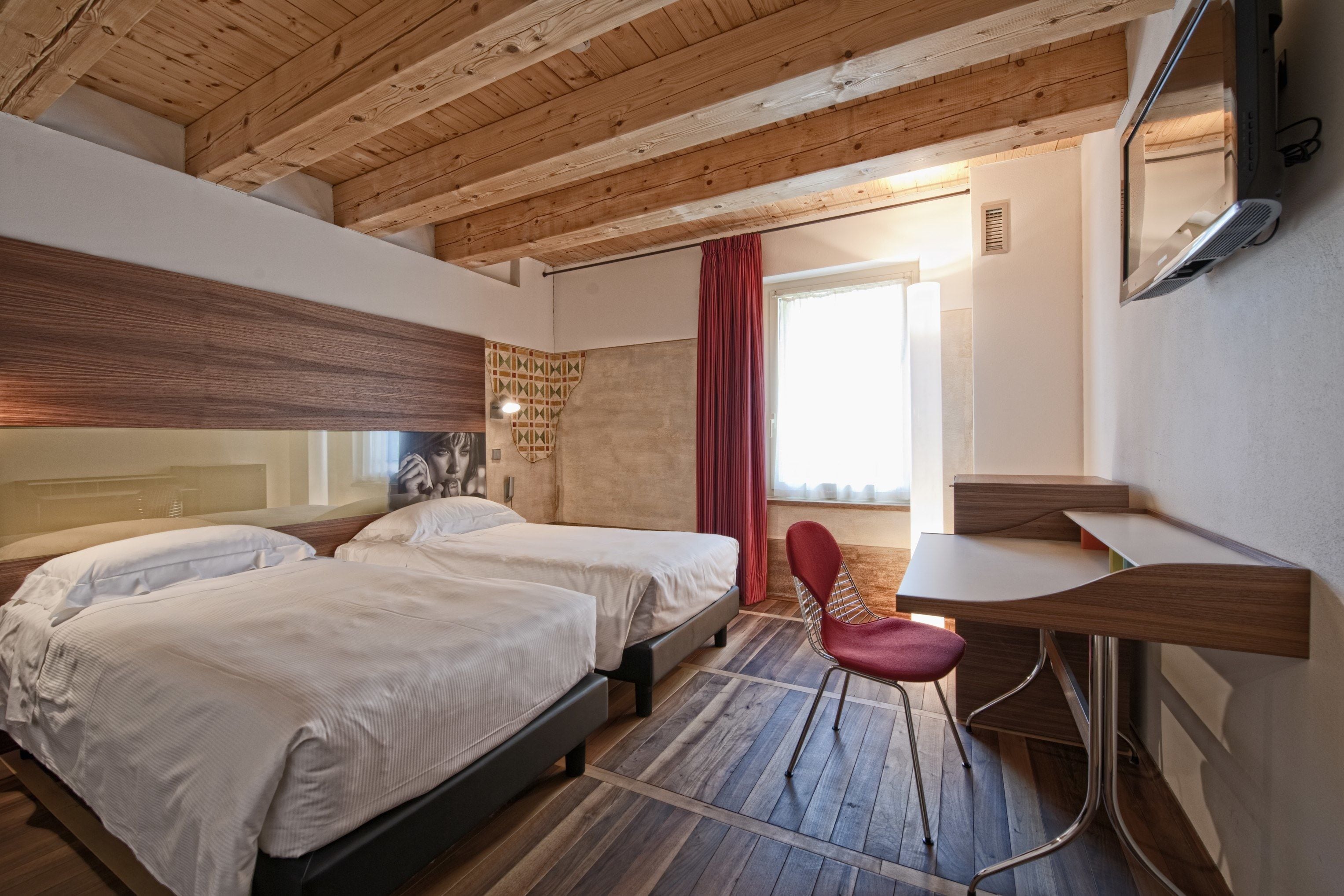 A modern bedroom with two beds, a desk, and a chair.