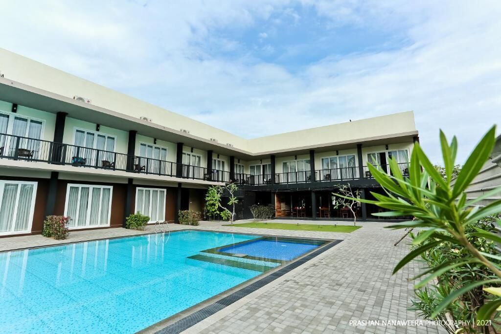 A hotel with a swimming pool, multiple balconies, and a courtyard.