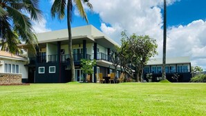 A modern hotel with a flat roof, multiple balconies, and a well-maintained lawn.