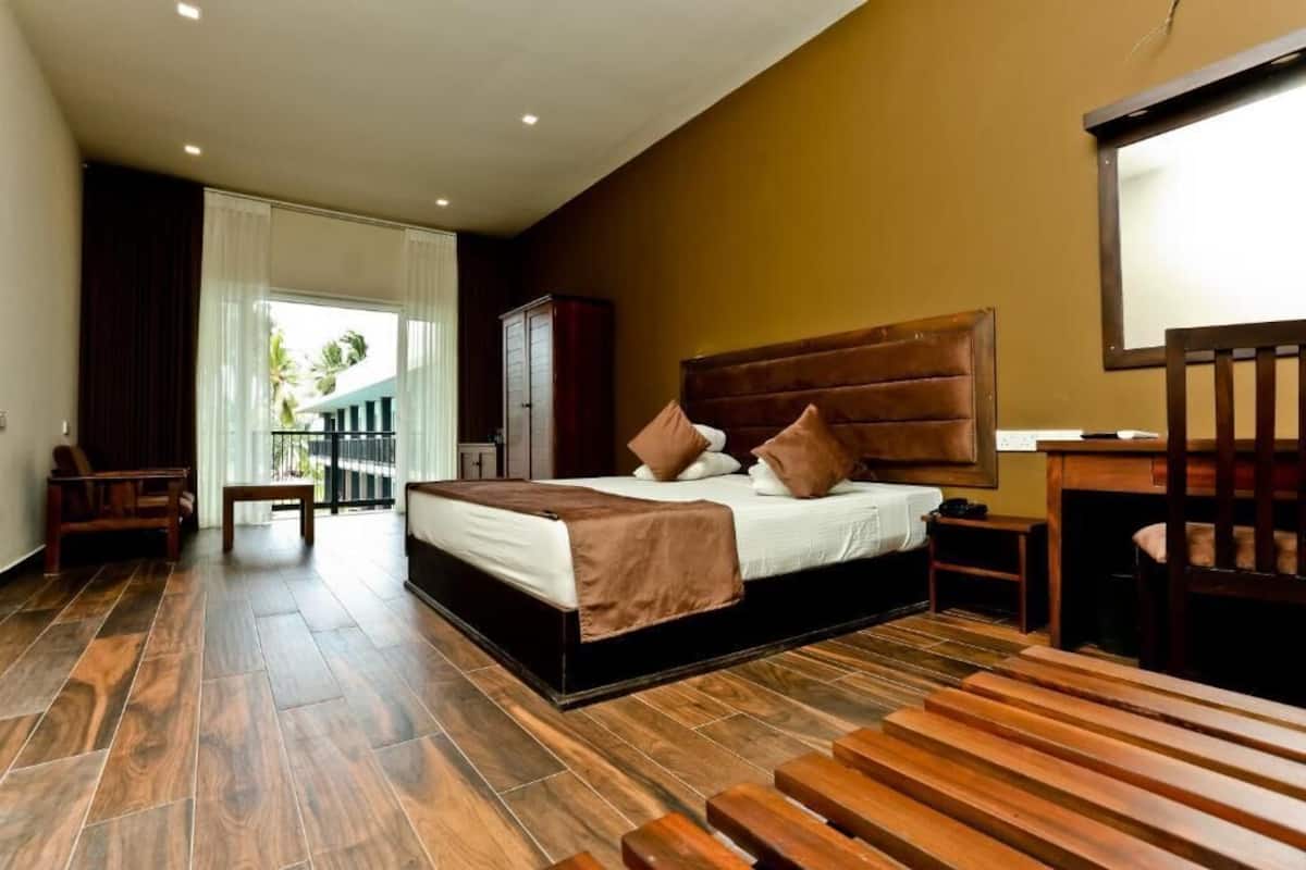 Ein modernes Hotelzimmer mit einem großen Bett, Holzboden, einem Schreibtisch und Blick ins Freie.