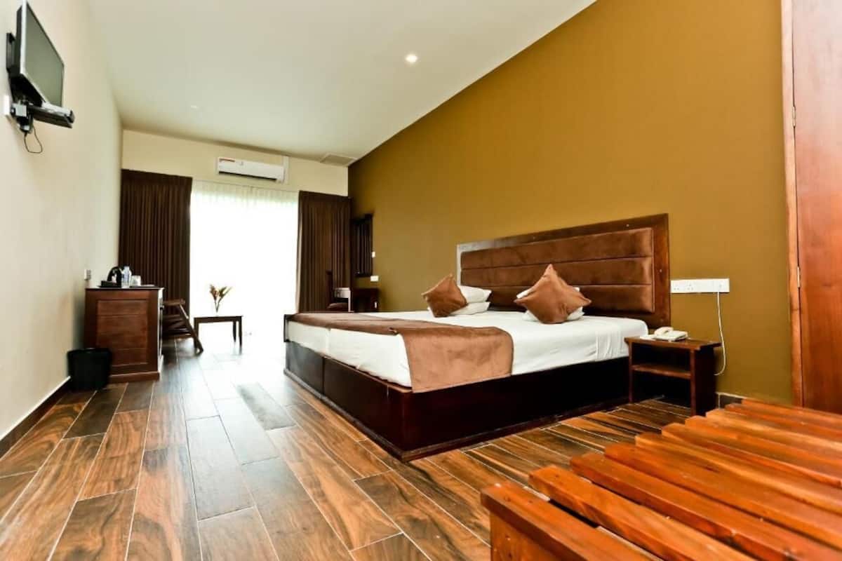 Ein Hotelzimmer mit einem großen Bett, Holzboden, einem Fernseher und einem Schreibtisch mit Lampe.