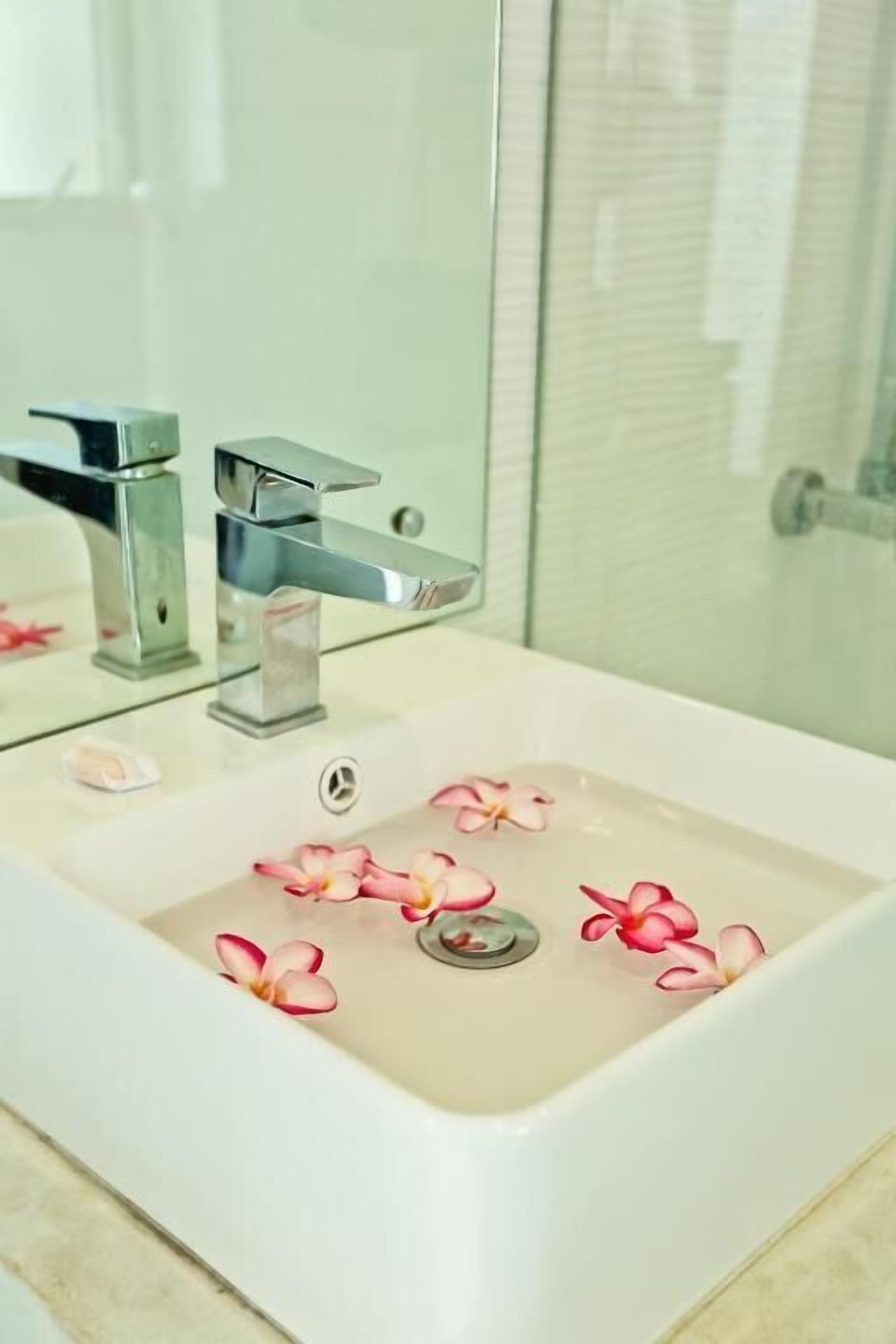 A bathroom with a white sink, a chrome faucet, and a glass shower enclosure.