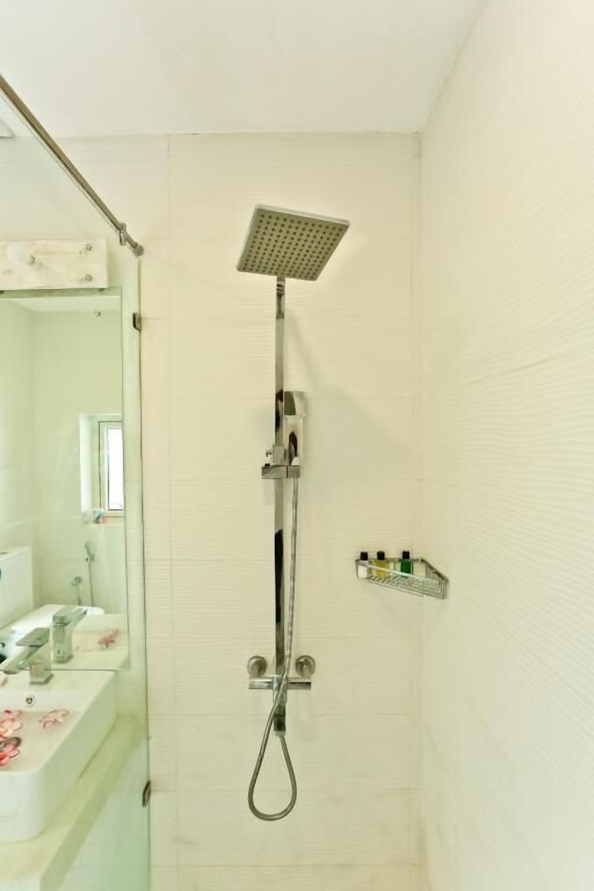 A bathroom with a shower, a mirror, and a shelf with toiletries.