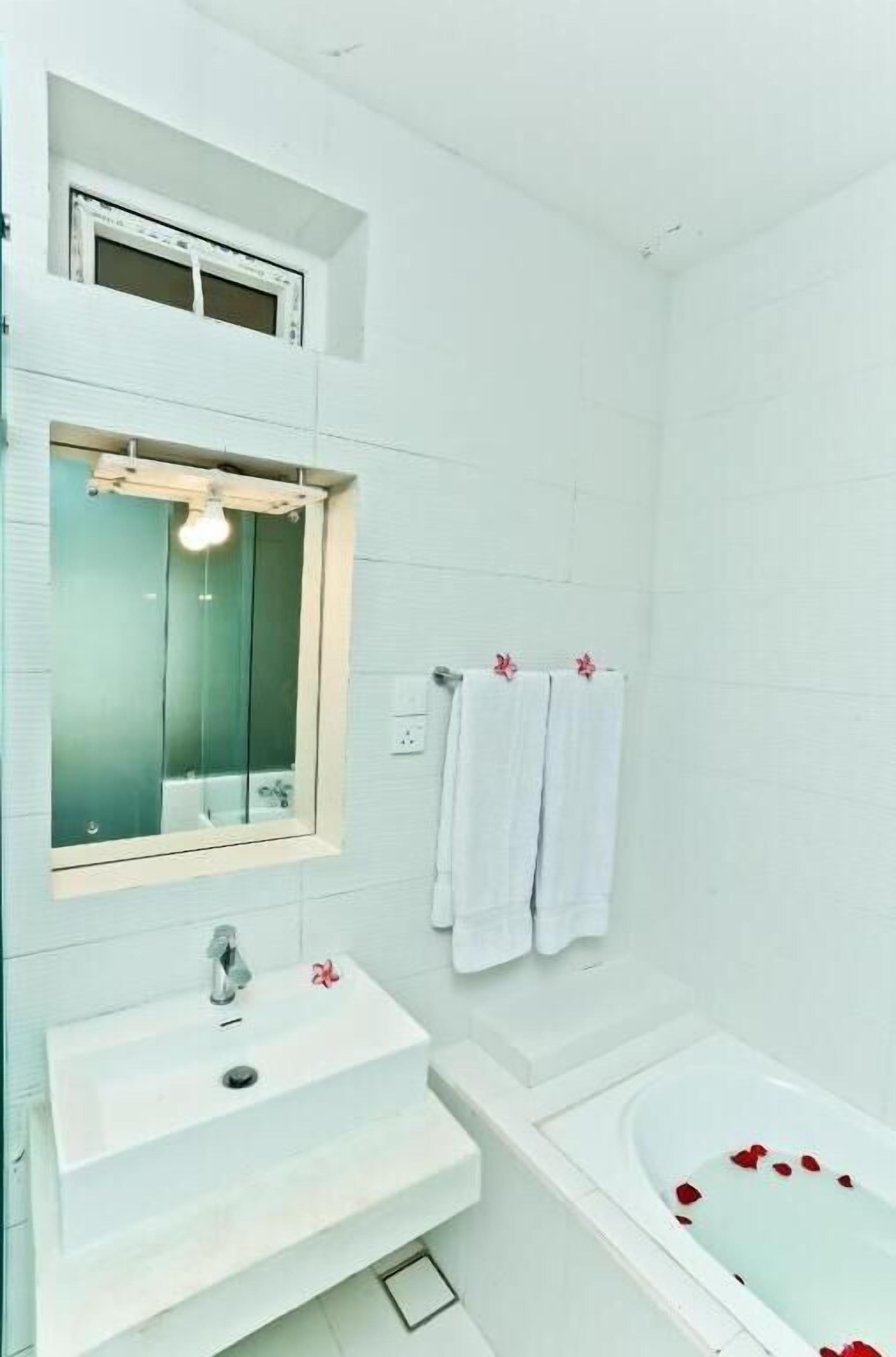 A bathroom with a white sink, mirror, and bathtub.