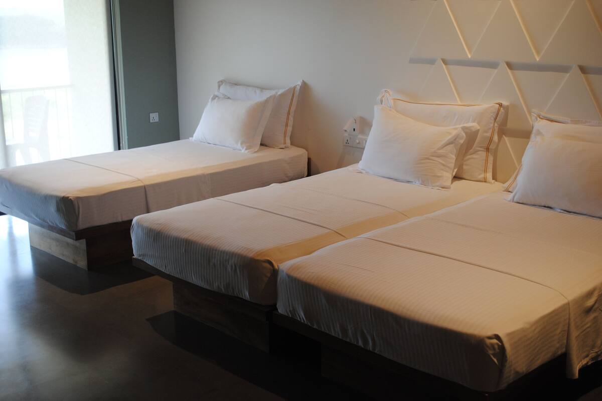 A hotel room with two single beds, each with a headboard and pillows.