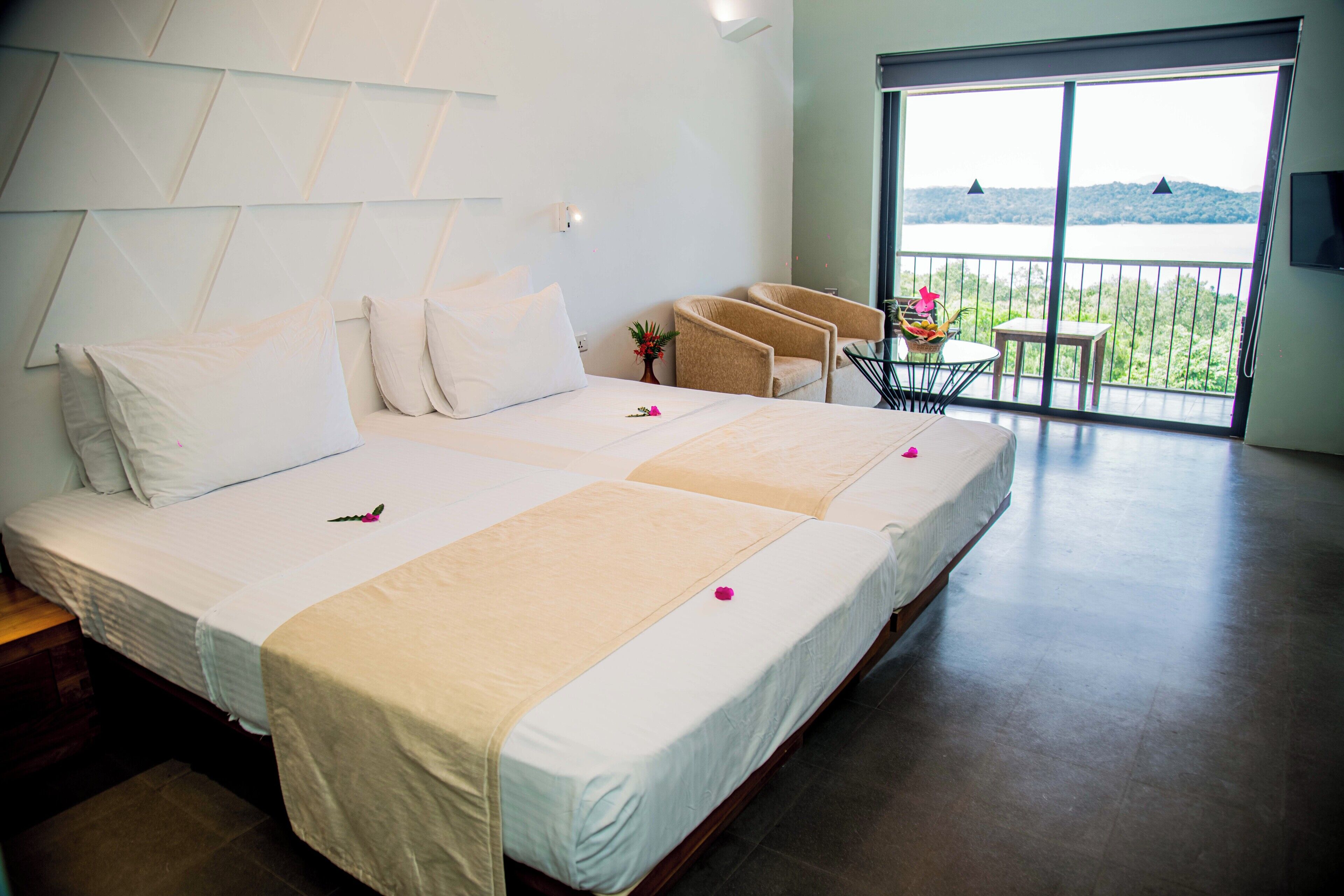 Habitación de hotel con una cama grande, un balcón con vistas y una pequeña mesa con sillas.