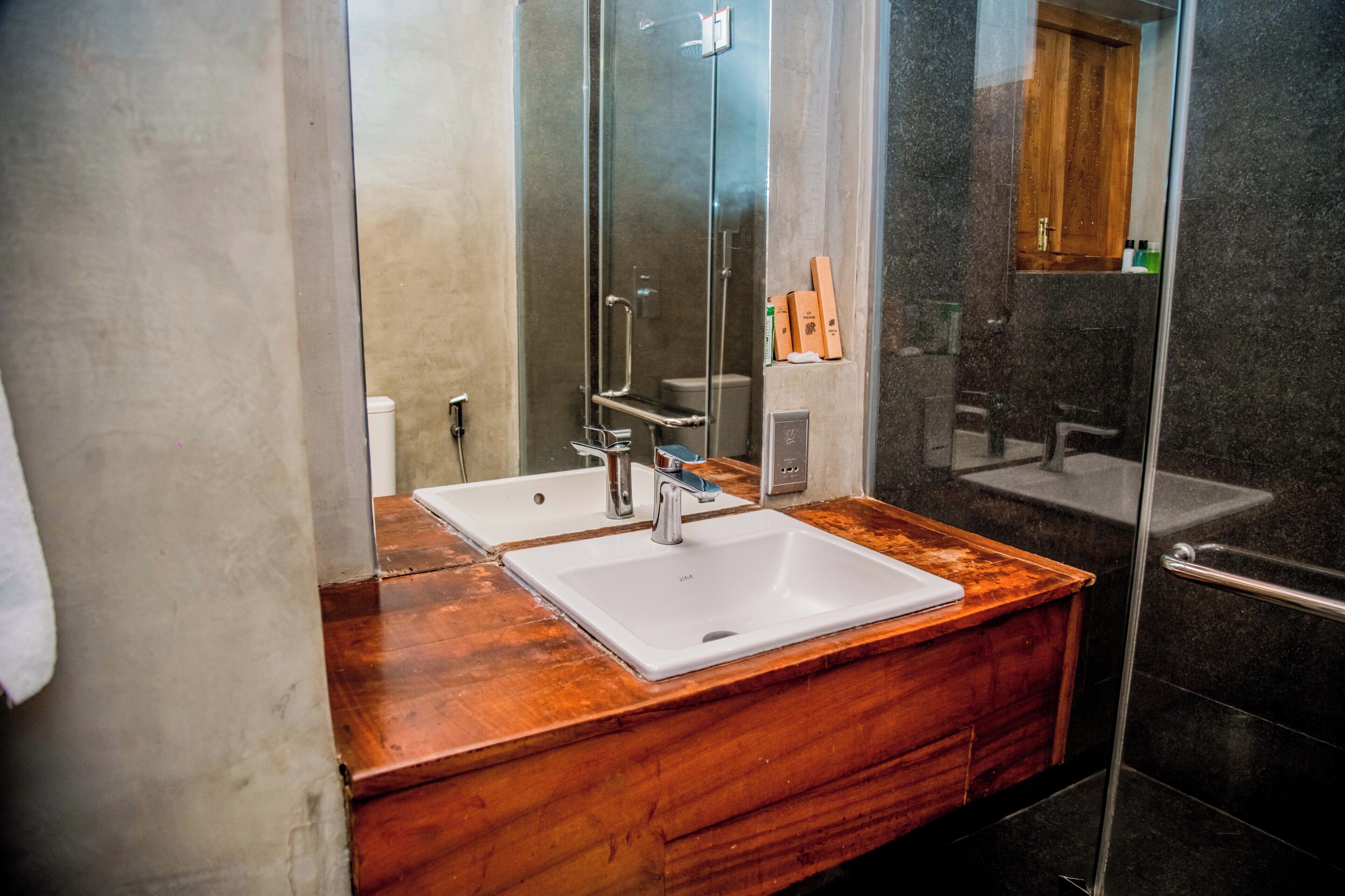 Un baño moderno con tocador de doble lavabo, cabina de ducha con mampara de vidrio y encimera de madera.