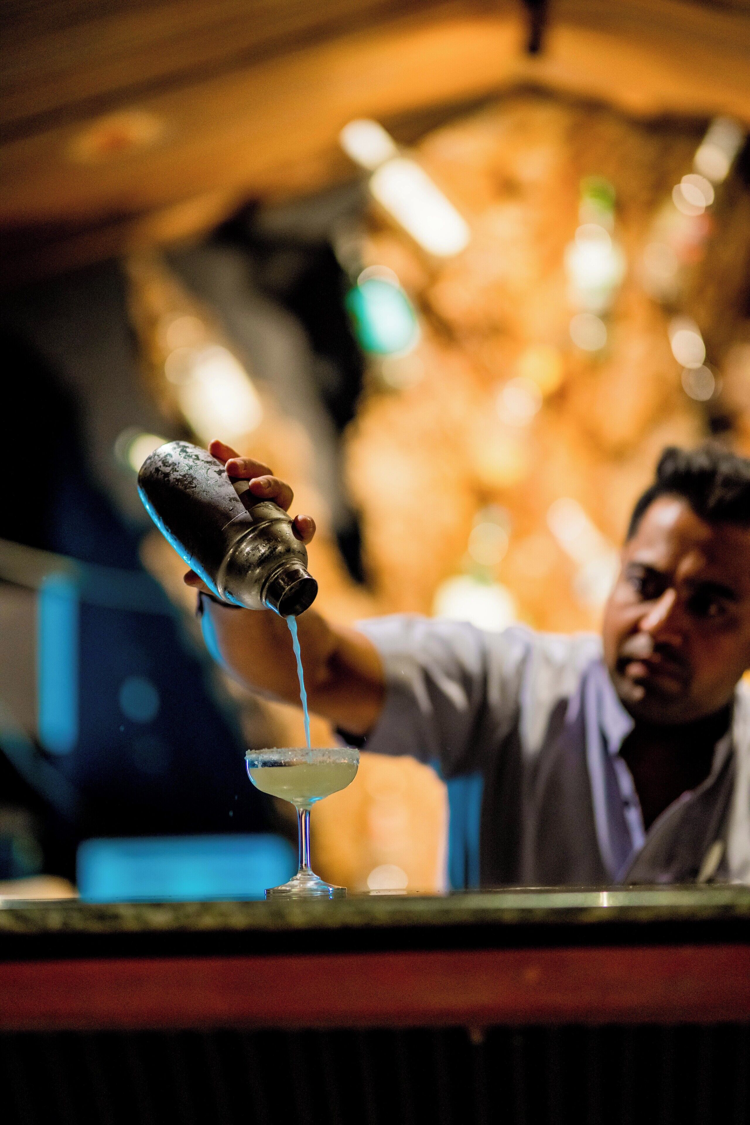 Un barman verse une boisson dans un verre.