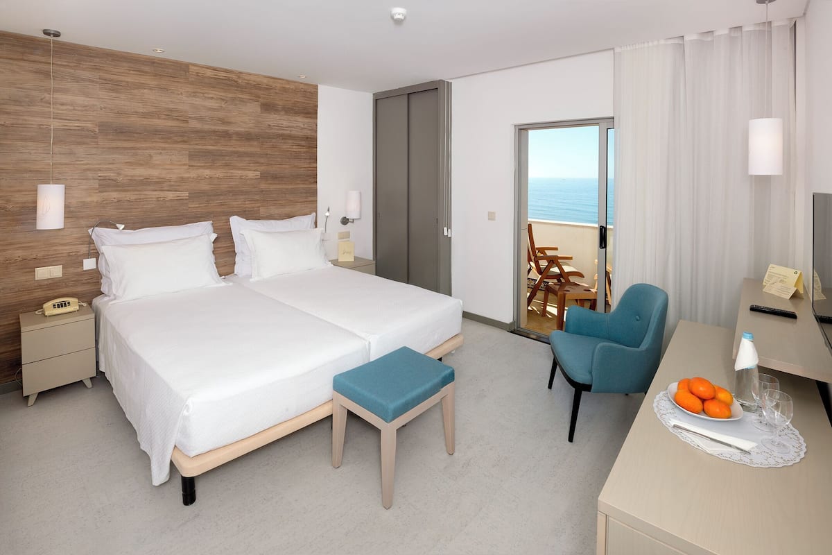 A hotel room with a bed, bedside table, desk, chair, and a TV.