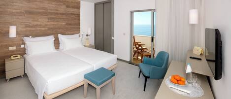 A hotel room with a bed, bedside table, desk, chair, and a TV.