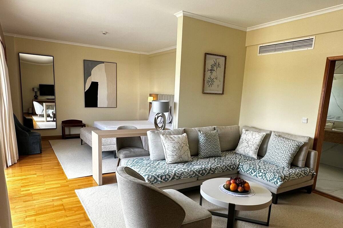 A modern living room with a sectional sofa, a round coffee table, and a grey armchair.