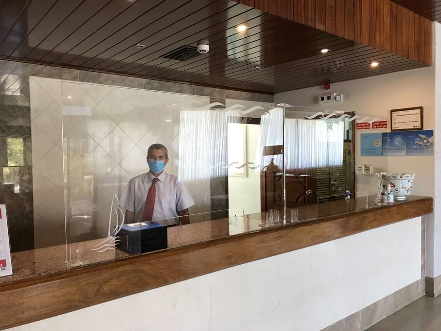 Zona de recepció amb una recepcionista, taulell de recepció, sostre de fusta i una paret amb diplomes emmarcades.