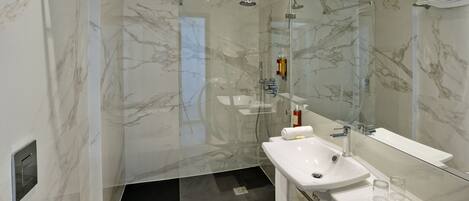 A modern bathroom with a glass-enclosed shower, a white sink, and a large mirror.