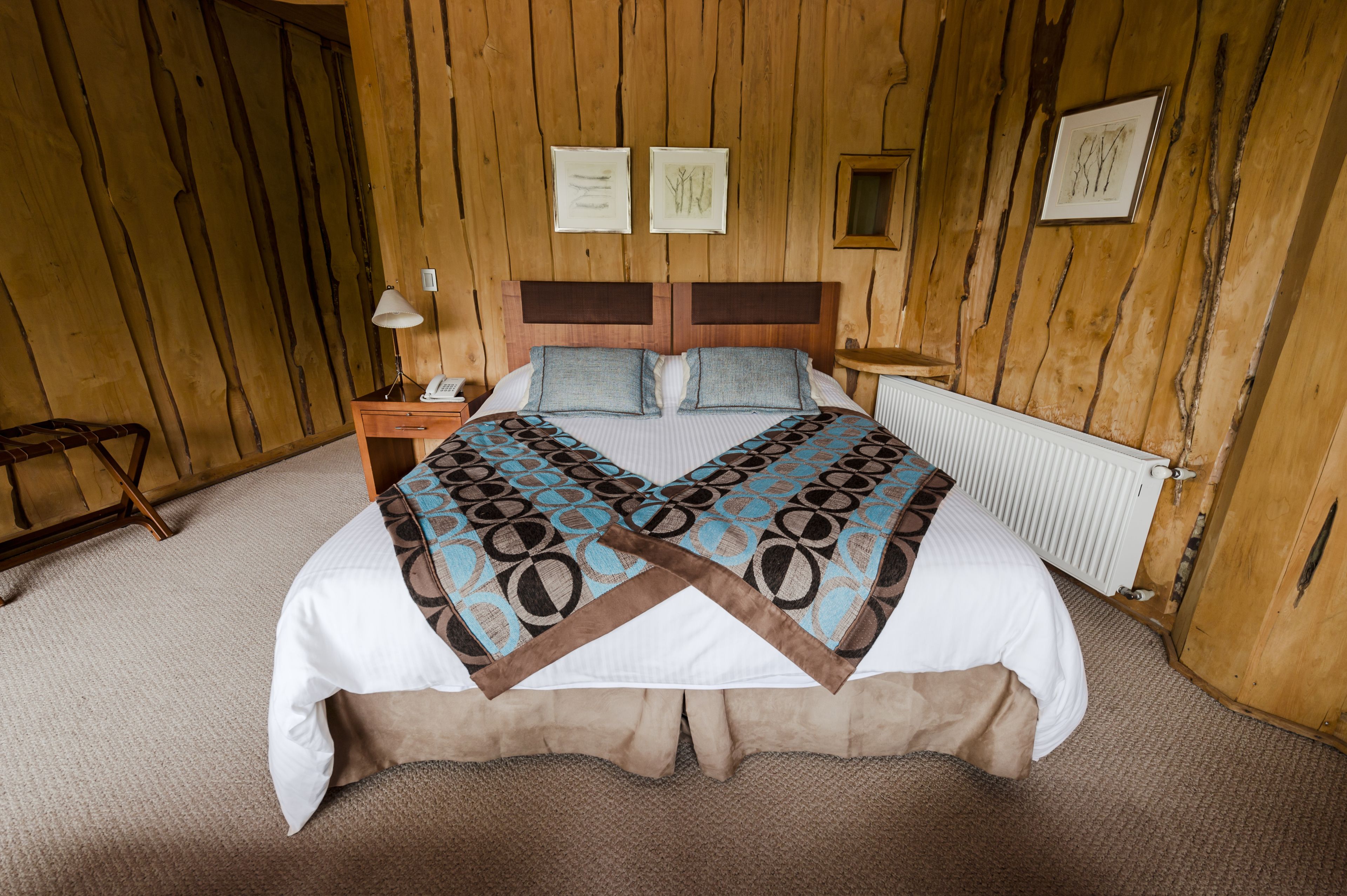 A wooden-paneled room with a bed, a nightstand, and a chair.