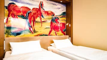 A hotel room with a large painting of horses on the wall, two beds with white linens, and a wooden headboard.