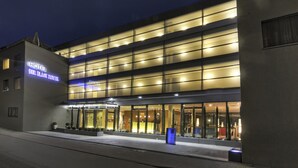 A modern hotel with a glass facade and illuminated signage. - Hotel Der Blaue Reiter Design- & Tagungshotel (Karlsruhe)